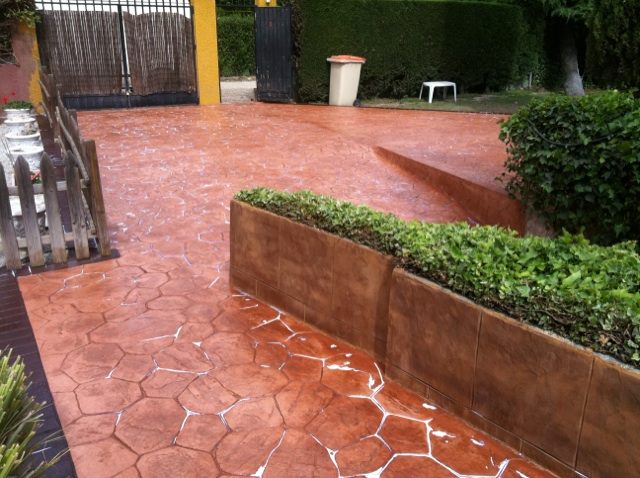 Patio ajardinado con hormigón impreso de color terracota
